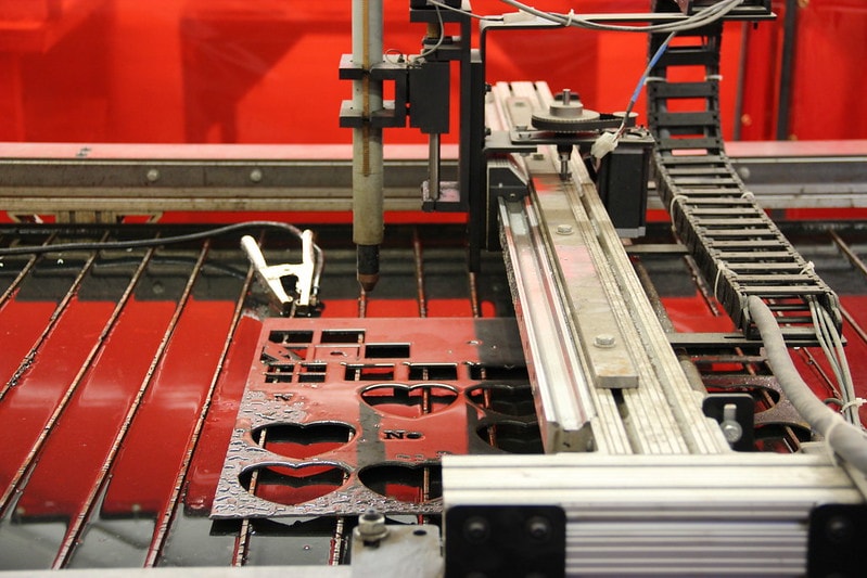 A plasma cutter working to cut heart shapes on metal How To Use a Plasma Cutter featured photo